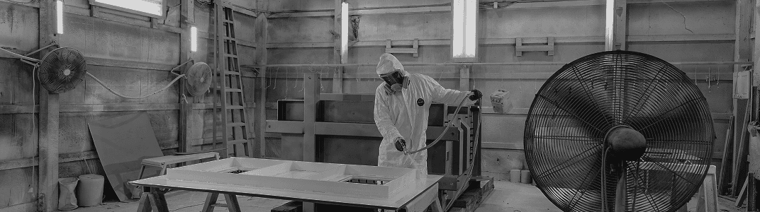 A person with a paint hose finishing a coat of paint on a table