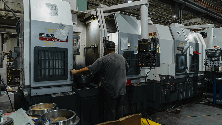 A CNC machine with a person standing over it, monitoring it