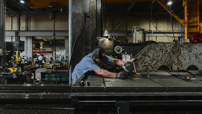 A pattern making machine at an industrial shop, show a man hard at work by the machine